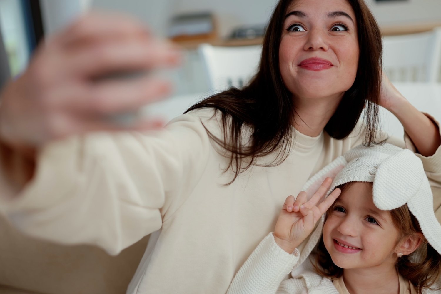 Uśmiechnięte matka i córka robią sobie selfie na kanapie w domu