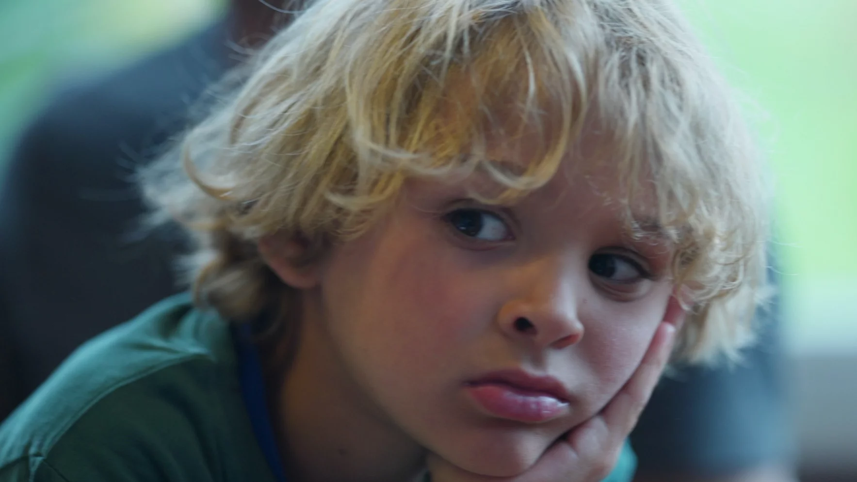 Na zdjęciu chłopiec siedzi znudzony.