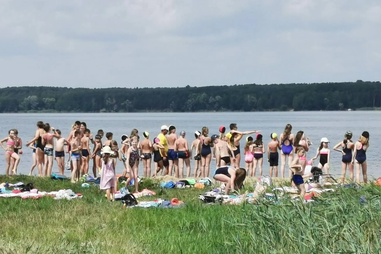Dzieci na koloniach plażują nad jeziorem.