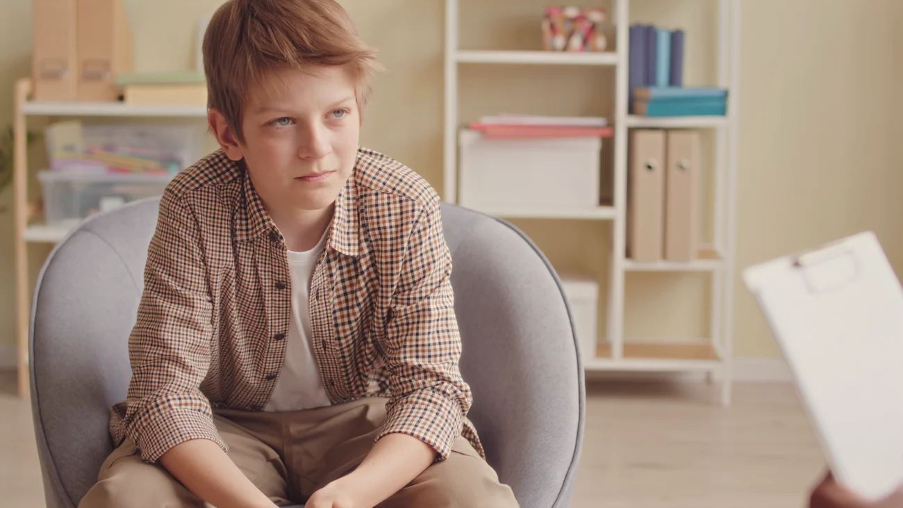 Jak wybrać psychoterapeutę dla dziecka Na zdjęciu widać chłopca siedzącego u specjalisty.