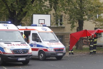 Zaparkowane pod szkołą karetki pogotowia.