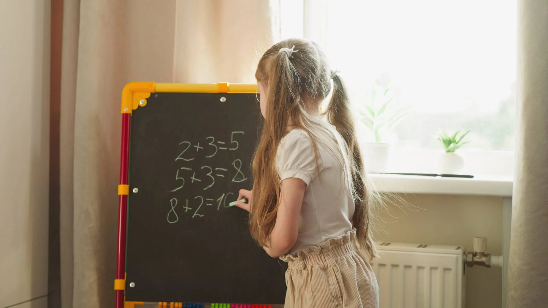 dziewczynka bawi się w szkołę i pisze na tablicy równania matematyczne dziewczynka bawi się w szkołę i pisze na tablicy równania matematyczne