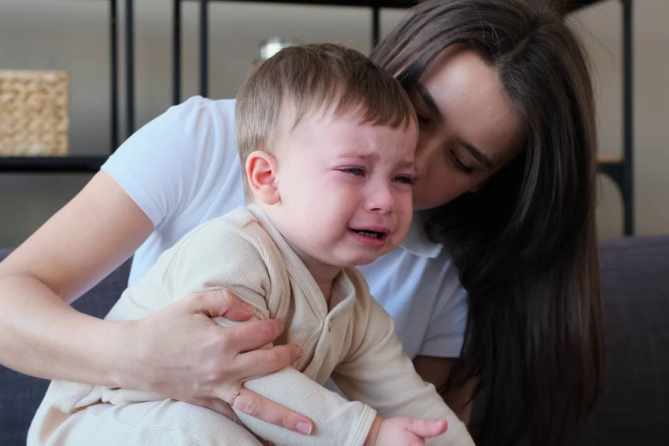 płaczące dziecko na kolanach mamy