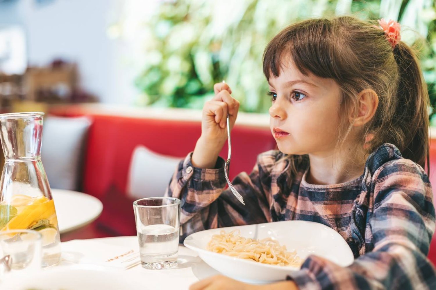 Mała dziewczynka przy stole w restauracji je posiłek.