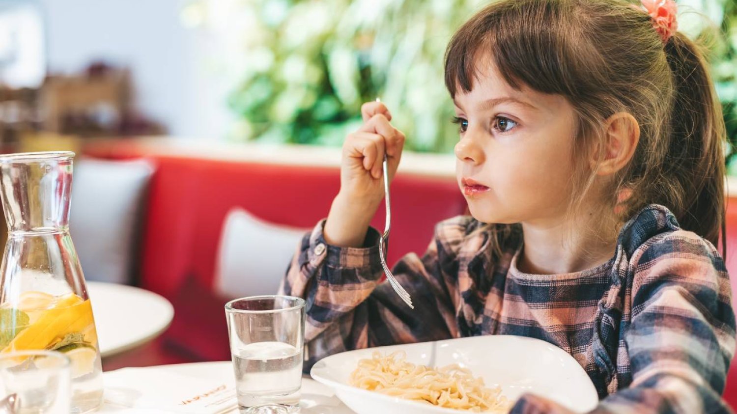 Mała dziewczynka przy stole w restauracji je posiłek.