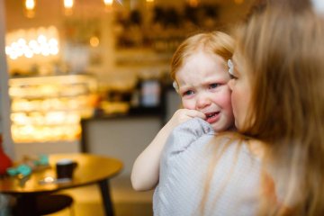 Mała dziewczynka płacze w restauracji i przytula się do mamy.