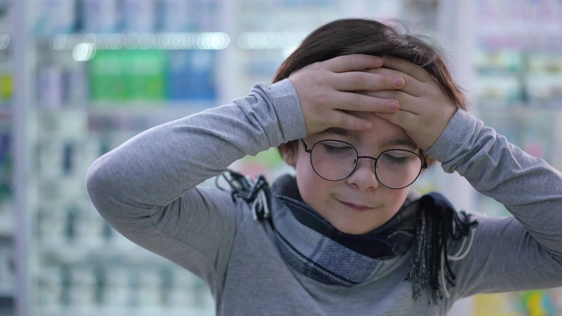 Chłopiec trzyma się za głowę i masuje skronie Chłopiec trzyma się za głowę i masuje skronie