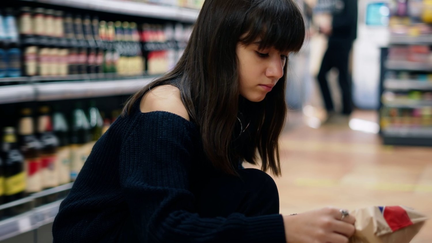 Na zdjęciu widać dziewczynkę–nastolatkę, która robi zakupy w supermarkecie.