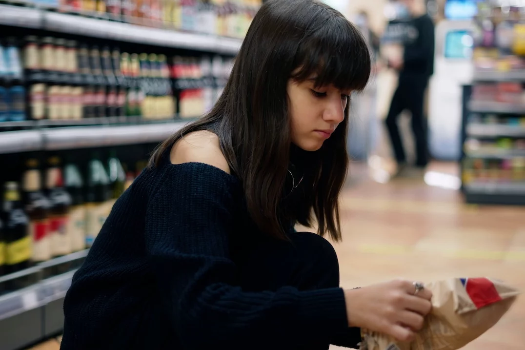 Na zdjęciu widać dziewczynkę–nastolatkę, która robi zakupy w supermarkecie.