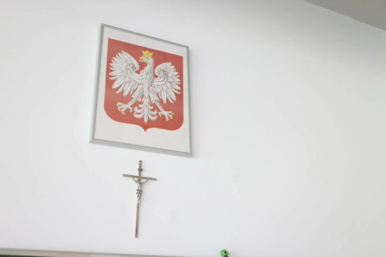 Krzyż oraz godło Polski na ścianie w szkolnej sali.