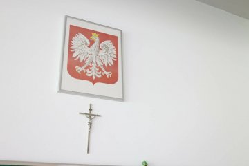 Krzyż oraz godło Polski na ścianie w szkolnej sali.