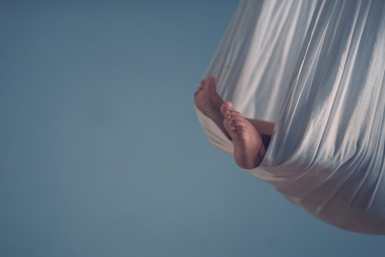 Bose stopy dziecka bujającego się w chuście.