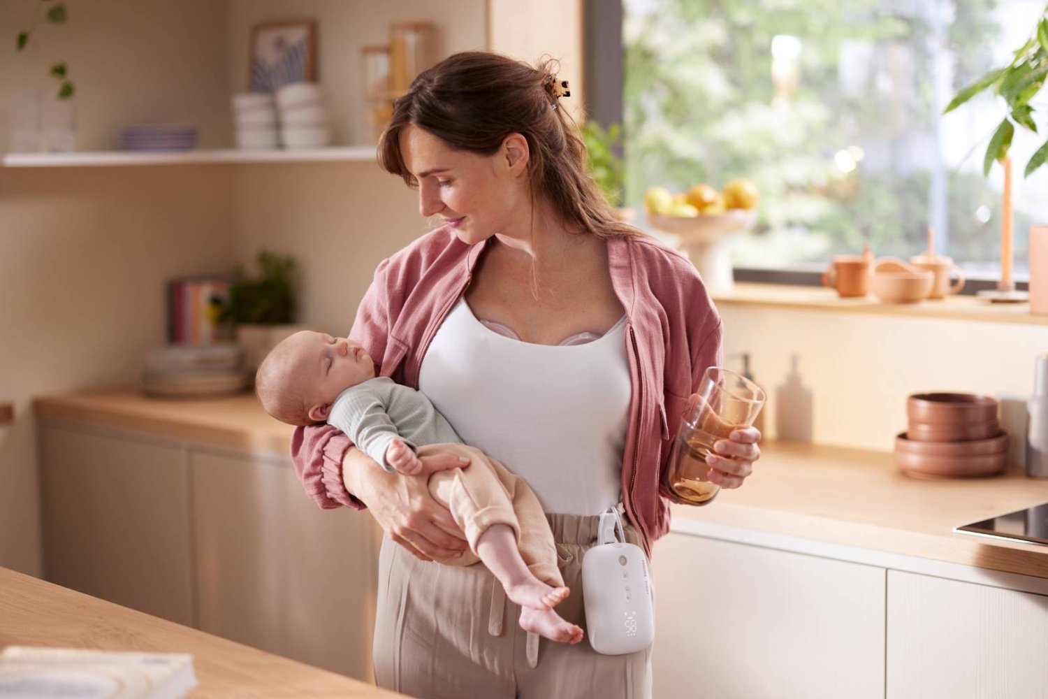 mama z dzieckiem na rękach równocześnie odciąga mleko laktatorem