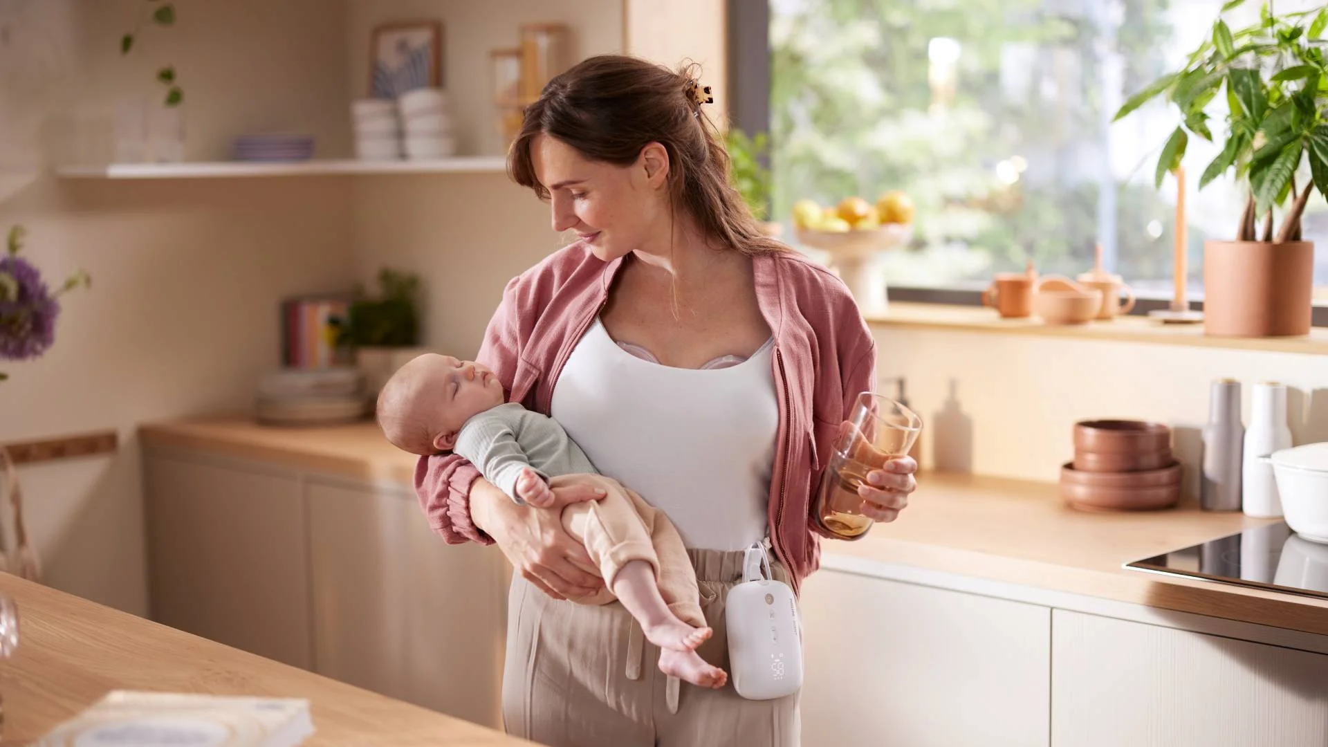 mama z dzieckiem na rękach równocześnie odciąga mleko laktatorem