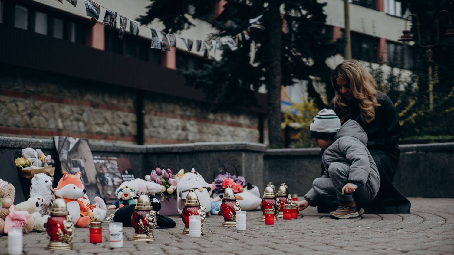 mama z dzieckiem zapala na pomniku znicz