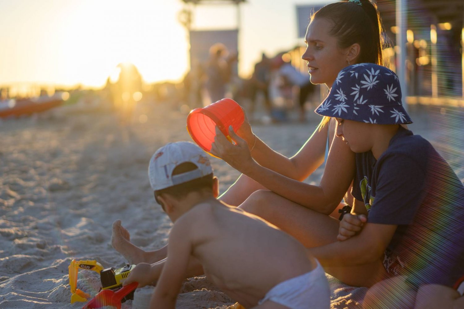 mama z dziećmi na plaży bawi się w piachu
