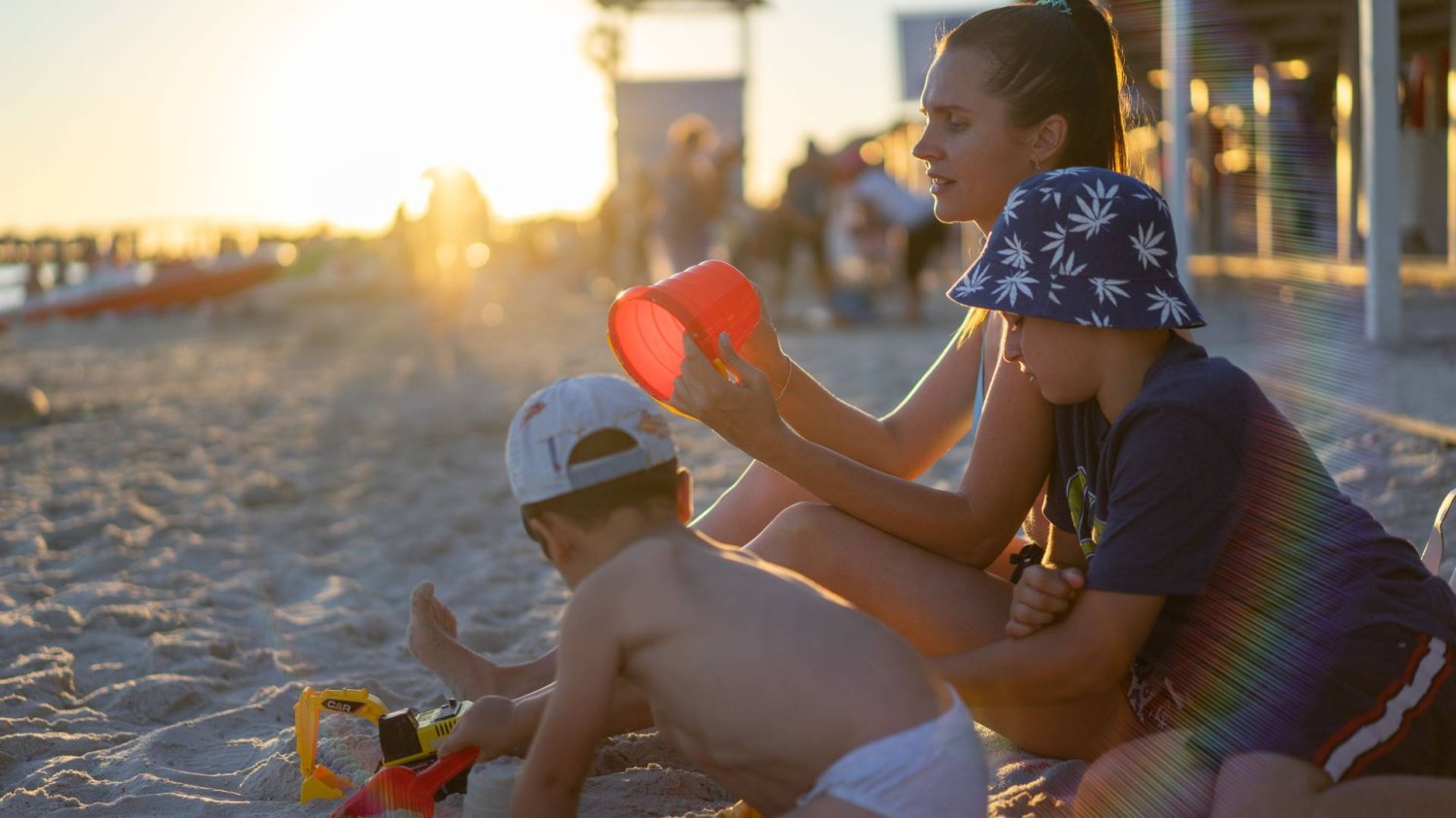 mama z dziećmi na plaży bawi się w piachu