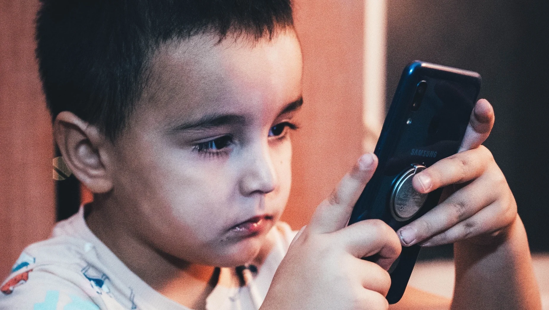 Autyzm wirtualny u dzieci. Te objawy powinny zwrócić uwagę rodziców Na zdjęciu chłopiec wpatrzony w telefon.