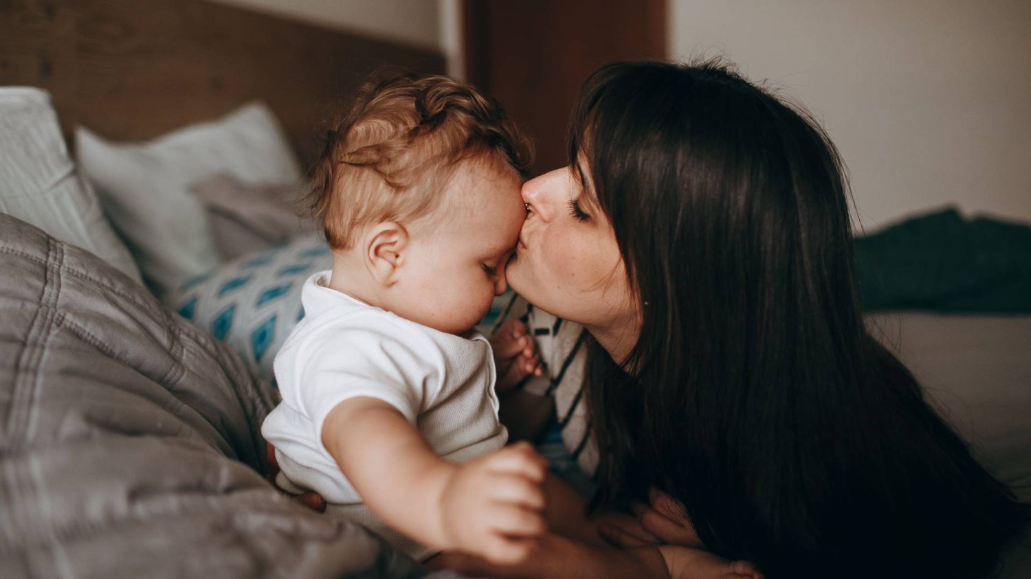 nadopiekuńcza mama całuje dziecko w czoło