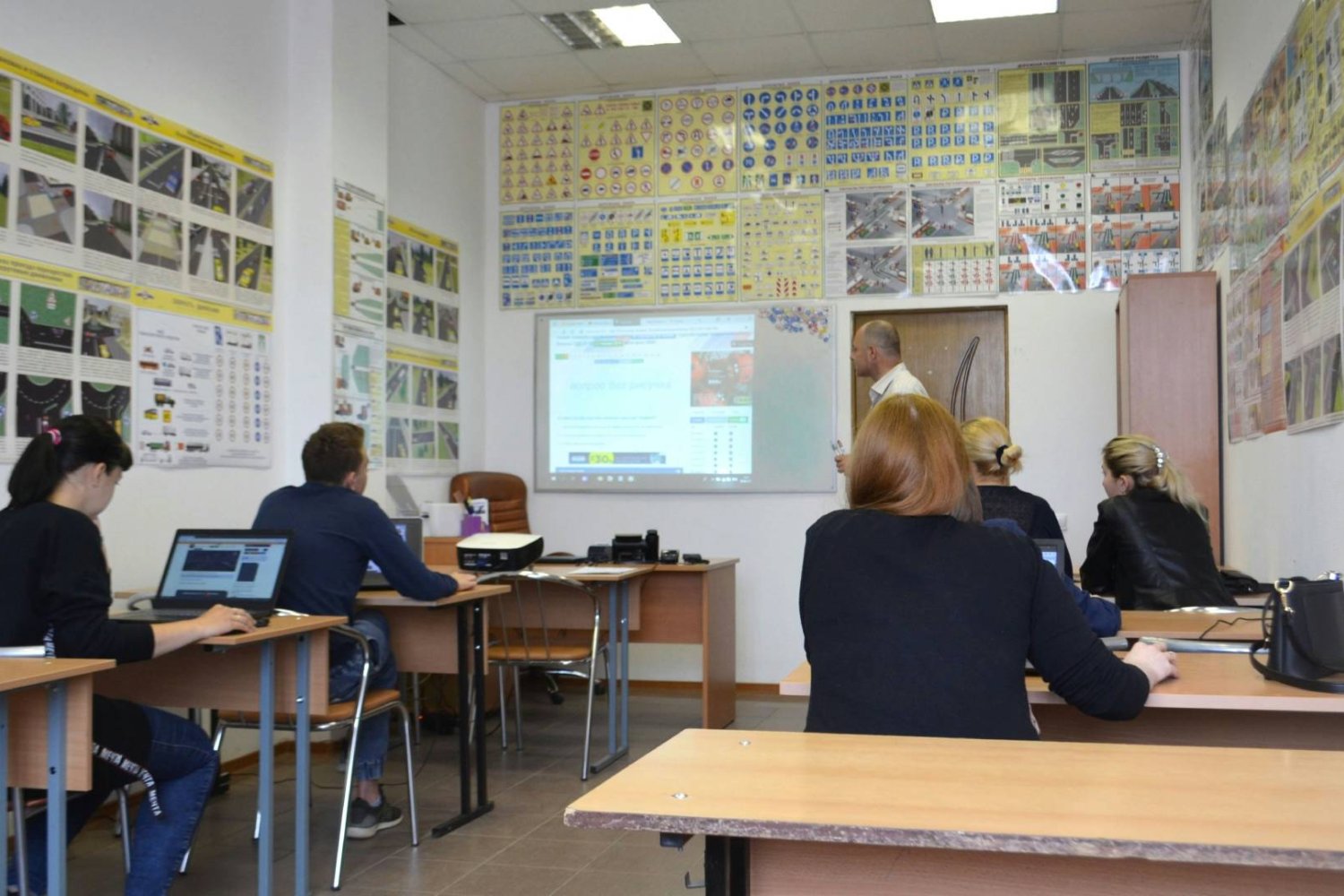 nauczyciel z uczniami w klasie prowadzi lekcję