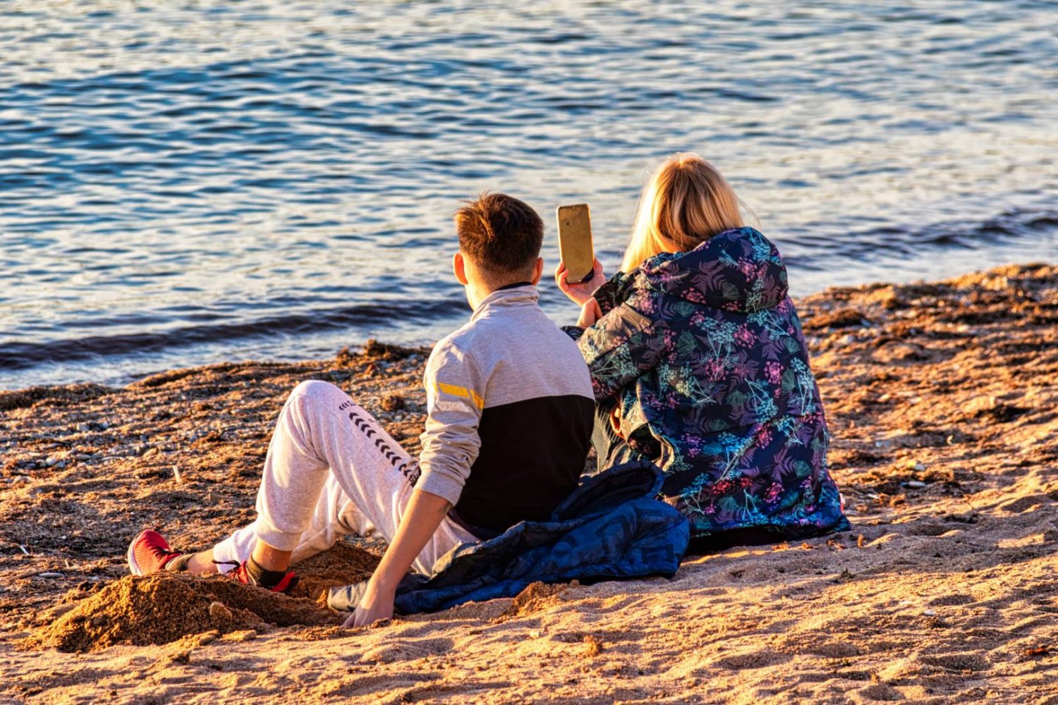 rodzice na plaży robią zdjęcia smartfonem