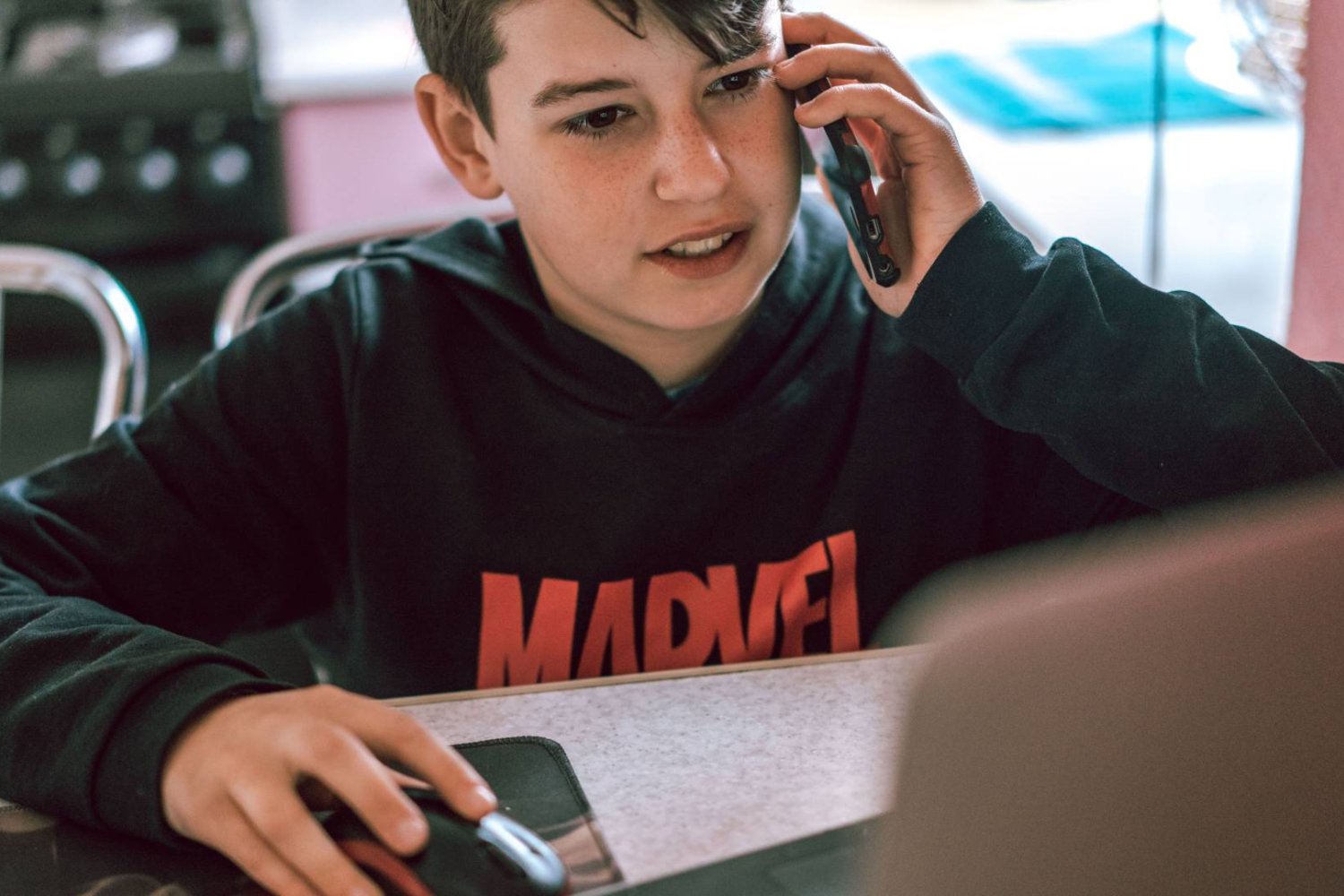 uczeń ze smartfonem siedzi przed komputerem