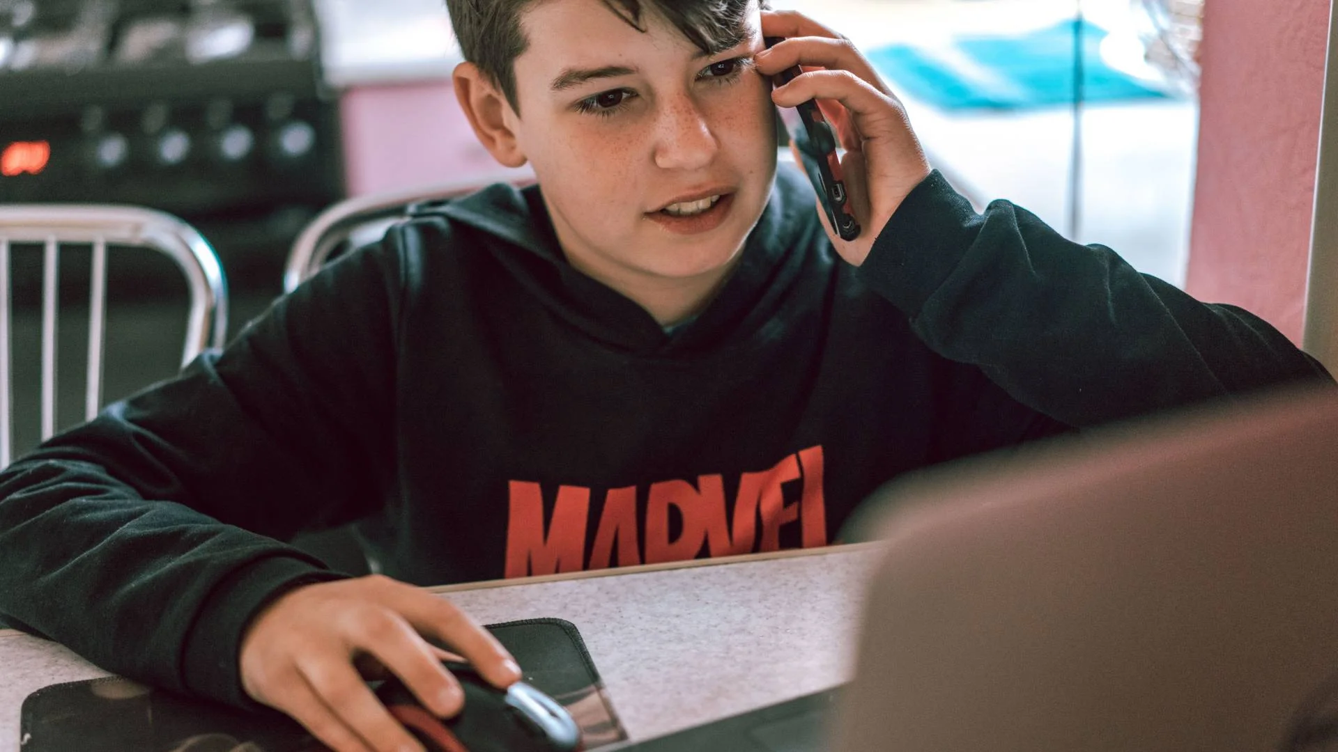 uczeń ze smartfonem siedzi przed komputerem