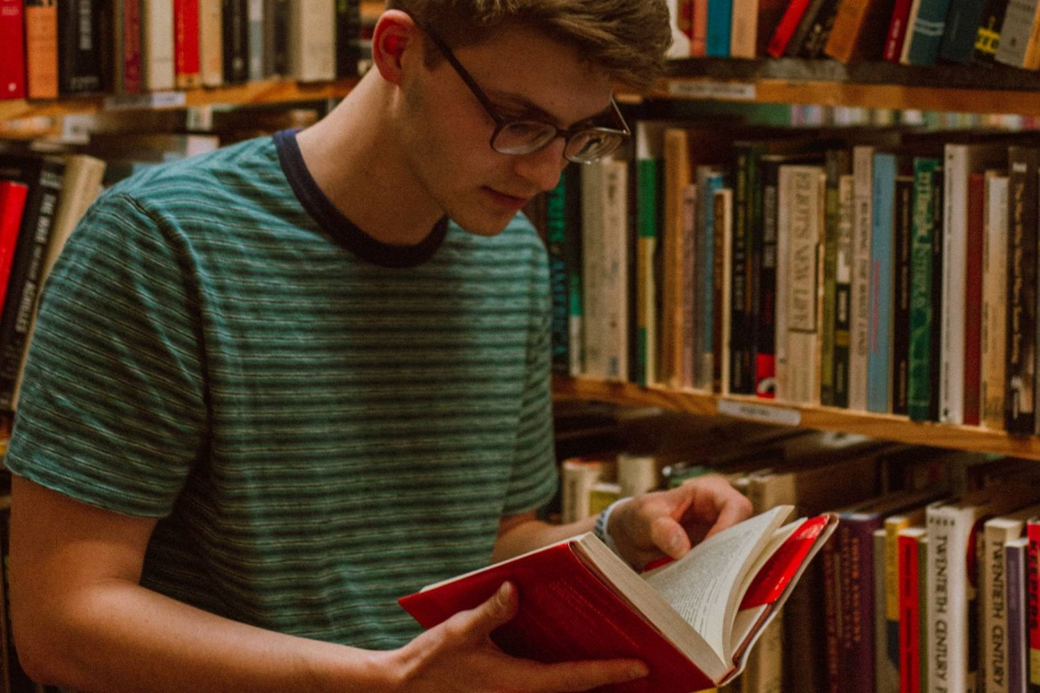 uczeń w bibliotece czyta książkę