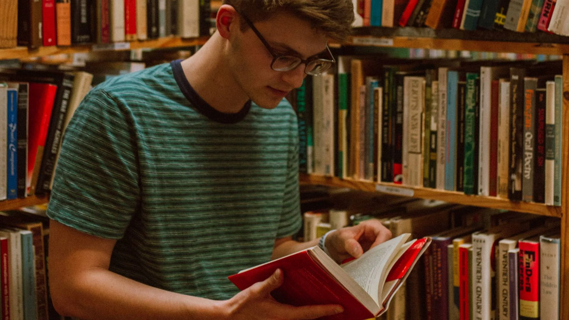 uczeń w bibliotece czyta książkę