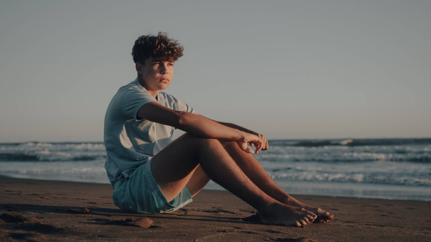 zamyślony nastolatek na plaży