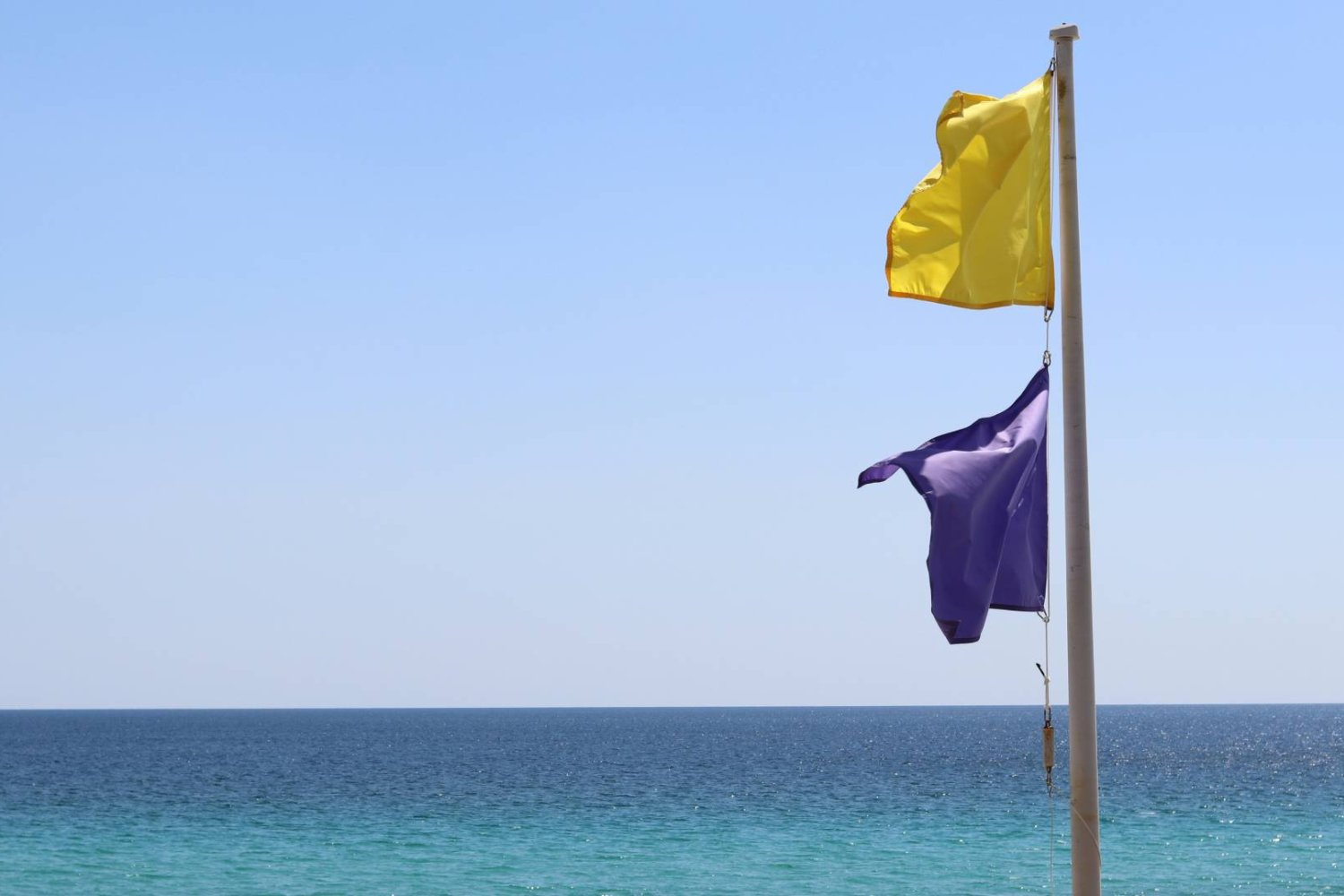 żółta flaga i fioletowa flaga na plaży nad morzem
